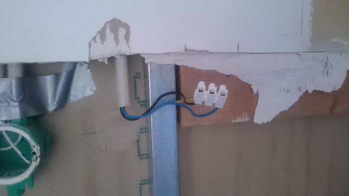 Oöppnat eluttag utan jordning med lösa sladdar och kabelskydd mot en vägg.