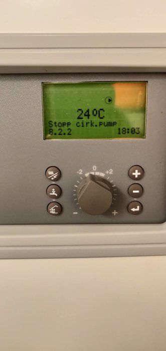 Digital termostat som visar 24°C, med knappar och reglage för värmejustering.