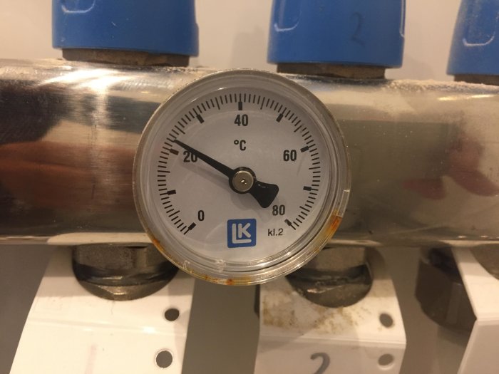 Termometer på en rörinstallation visar cirka 20°C, markerat med blått.