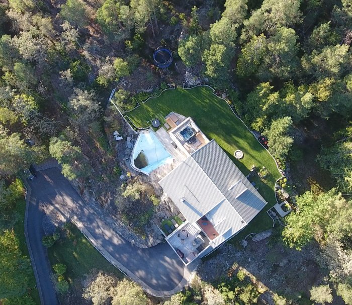 Flygbild över ett hus med trädgård, pool och omgivande natur "von oben".