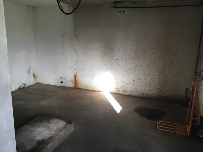 Ett tomt rum med vita lättbetongväggar och betonggolv som förberetts för renovering till verkstad.