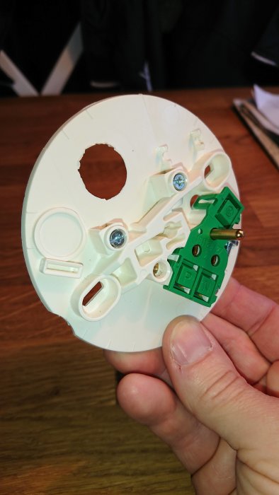 Hand håller ett lamputtag avsett för montage i trätak över en takdosa.