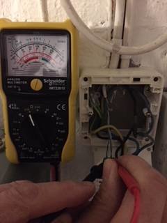 Multimeter som mäter motstånd på termostatgivarens sladdar med en hand som håller proberna.