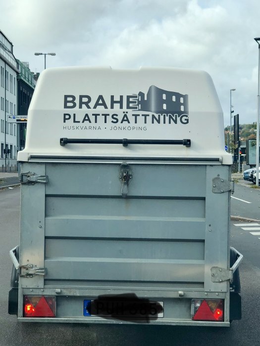 Bakdelen av en släpvagn med logga för "Brahe Plattssättning" som inkluderar en byggnadsruin i designen.