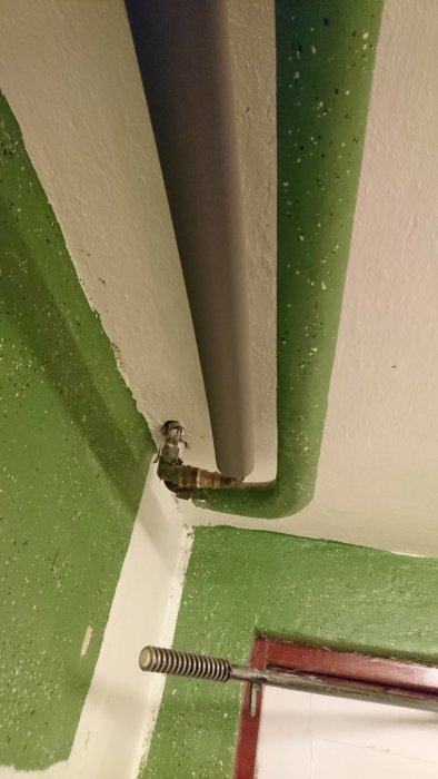 Kopplingspunkt mellan pex- och kopparrör i takhörn bredvid grönt rör och takstöd.