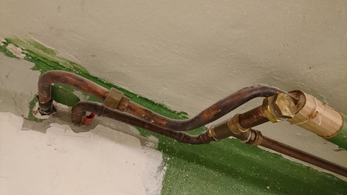 Kopparledningar och anslutningar mot en vägg med delvis synlig isolering.