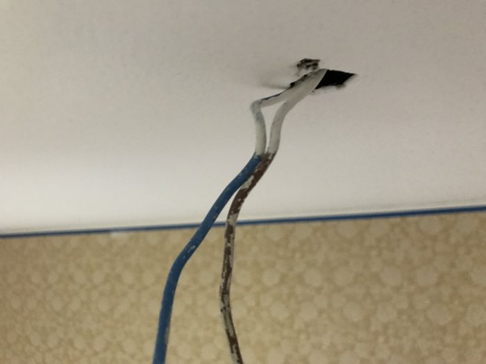 Vägg med en delvis avlägsnad tapet och synlig vävkonstruktion efter spärrvits applicering.