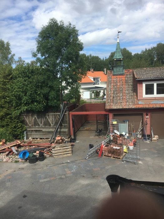 Rivningsmaterial och verktyg på en gård där taket på en carport har tagits bort i förberedelse för återuppbyggnad.