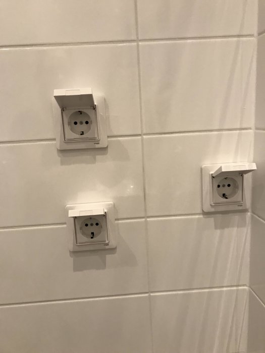Tre eluttag placerade osymmetriskt på en kaklad vägg, fel enligt byggöverenskommelse.