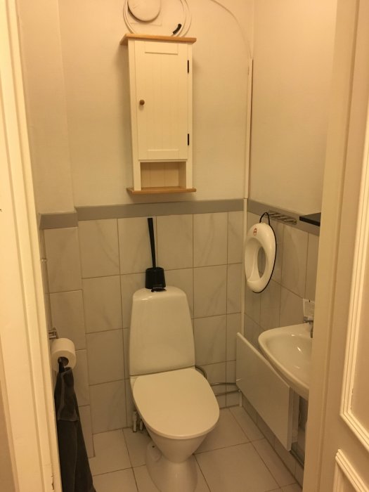 En toalett med en synlig kabel som löper längst taklisten och ner till en pax-fläkt över toaletten.