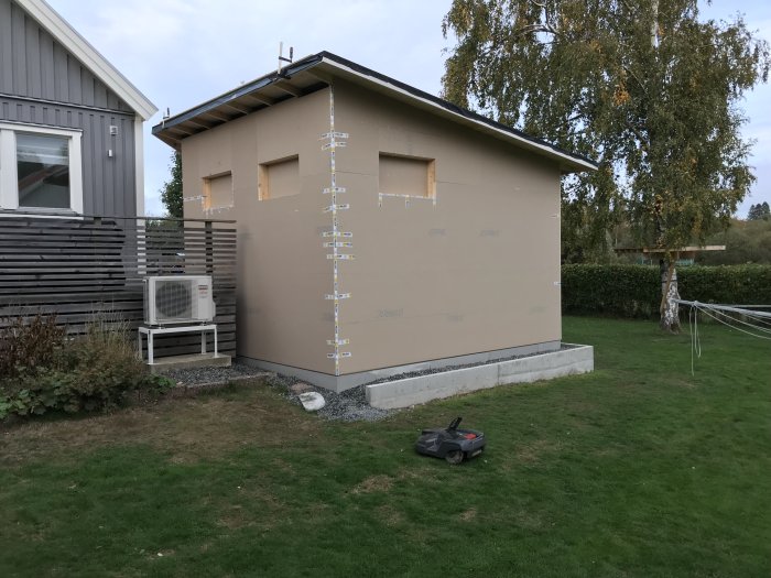 Nybyggd husdel med utegips och förberedda fönsteröppningar, väderskyddat för höst.