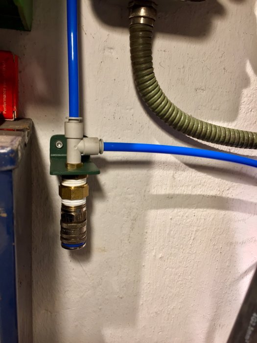 Väggmonterad vattenkoppling med ansluten blå PEX-rör och flexibel slang.