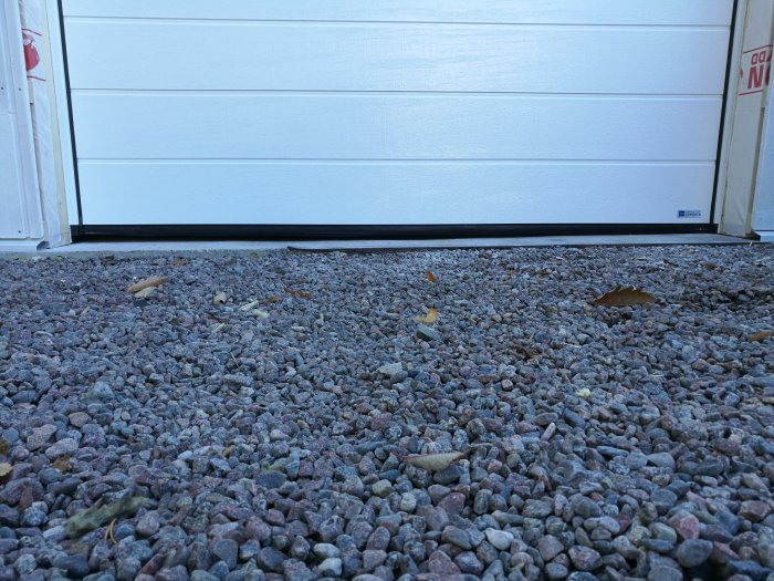 Nyinstallerad garageport med ojämn anslutning till grusuppfart, höjdskillnad synlig.