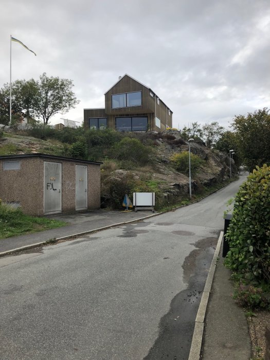 Modern villa på en klippa med nedmonterad ställning, delvis grånad fasad, i dagsljus.