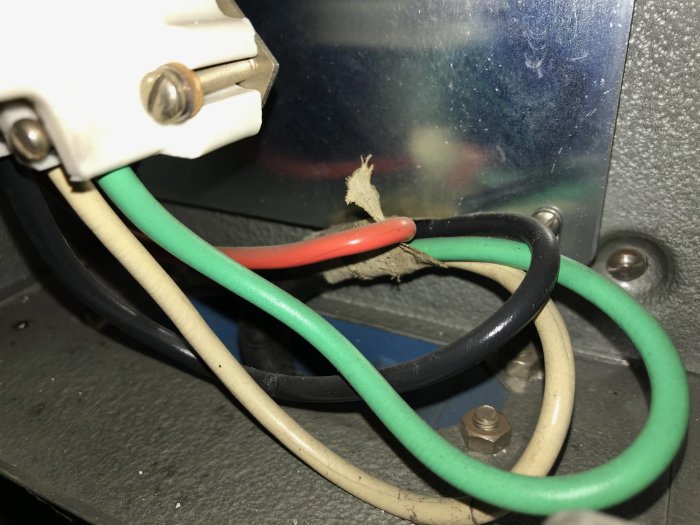 Gammal elektrisk kabel ansluten till en brytare med exponerade trådar och tecken på slitage.