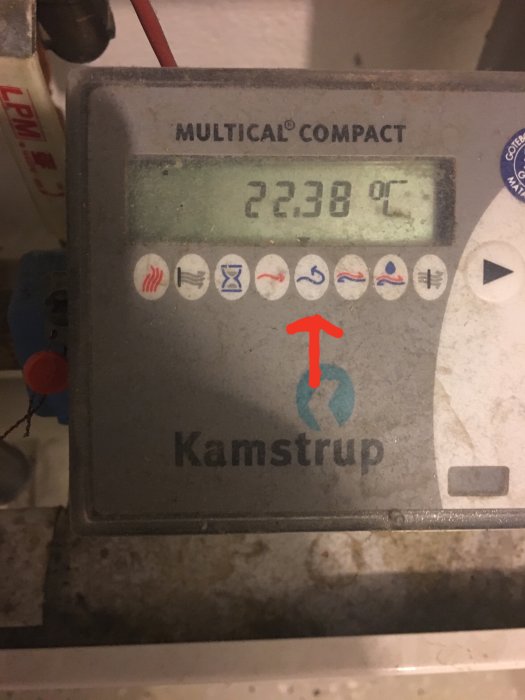 Kamstrup Multical Compact energimätare visar 22.38 °C, röd pil pekar mot justeringsikonen.