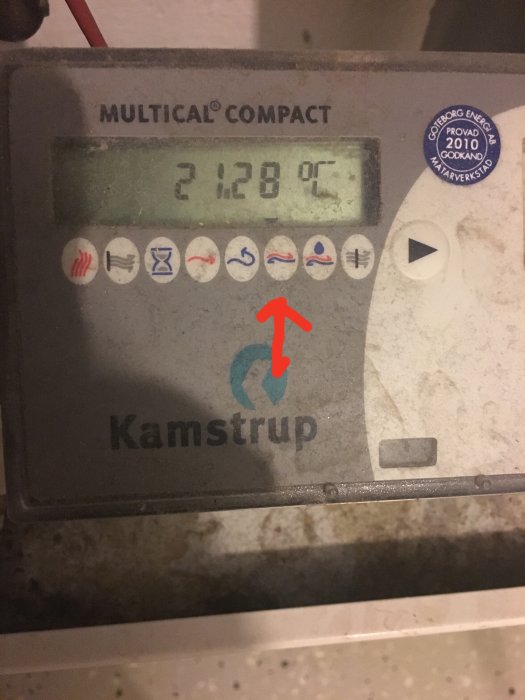 Multical Compact energimätare visar 21.28 grader med en röd pil som pekar på en ikon.