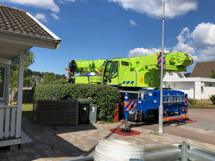 70-tons mobilkran parkerad på en bostadsgata, används för att flytta friggebod.