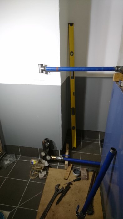 Installation av rörledningar med vattenpass och verktyg på byggarbetsplats.