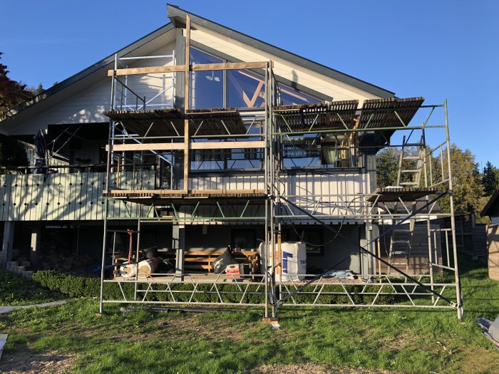 Hus under renovering med ny panel under fönster och ställningar runt byggnaden.