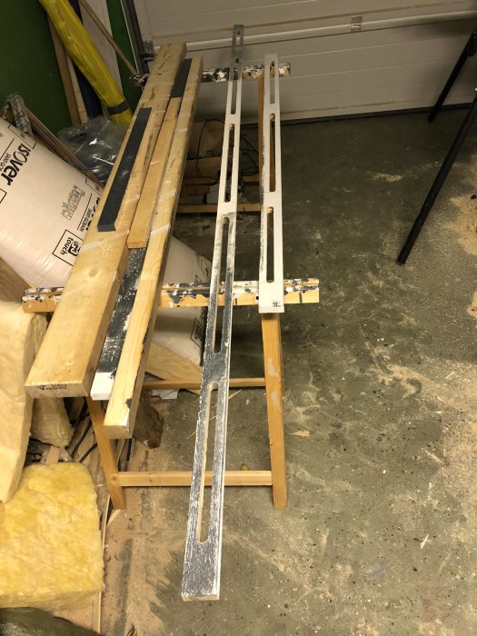 Träpanel med frästa salningar för luftning placerad på stöd i ett verkstadsutrymme.