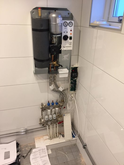 En värmecentral med expansionskärl, kontrollpanel och kopplingsbox, samt rörledningar och termostater.