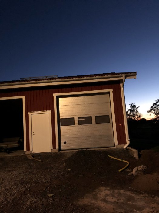 Garage med stängd port i skymningen, väntande på reparation eller byggnadsdelar.