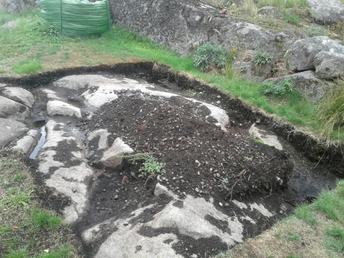 Utgåva för en betongram grund till ett växthus med ojämnt djup och synligt berg.