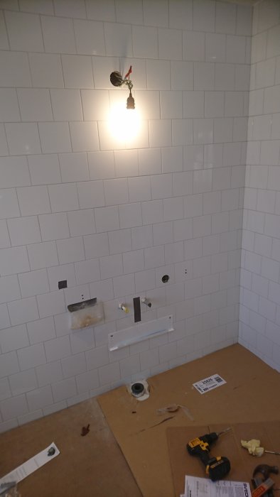 Badrum under renovering med kaklade väggar och installationsplats för handdukstork.