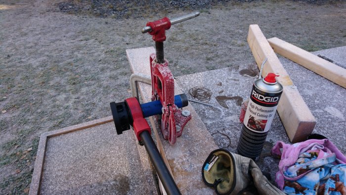 Rörmokarverktyg i arbete med frost på marken och rörskärningstillbehör.