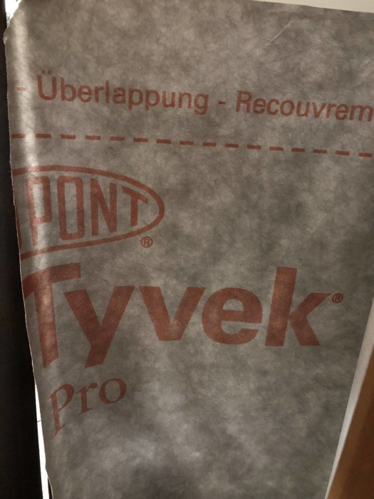 DuPont Tyvek Pro duk med texten "Uberlappung - Recouvrement" synlig, möjligen använd som takduk eller vindskydd.