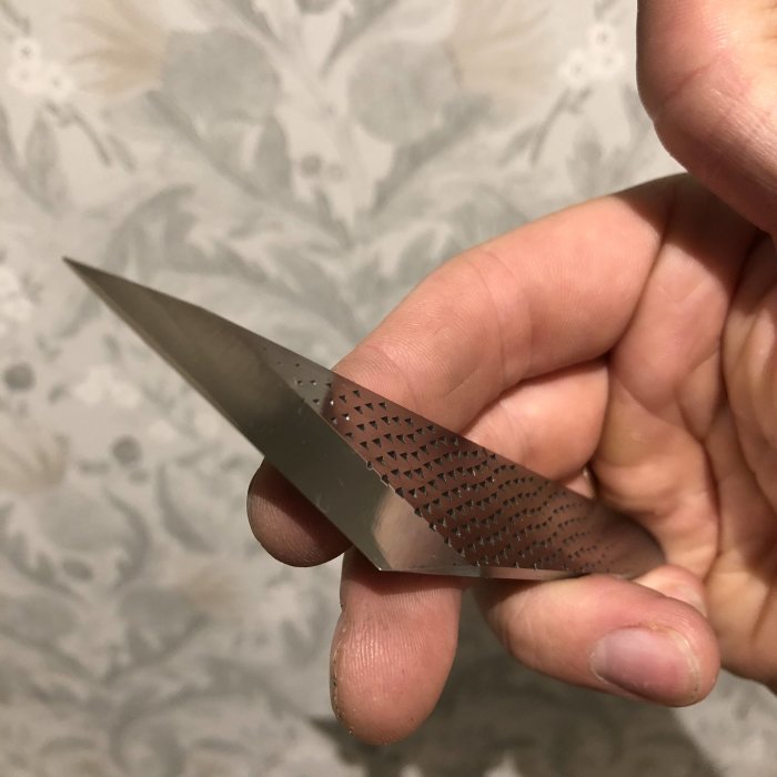 Hand håller ett nyslipat knivblad med distinkt mönster från GBO Sliperi.