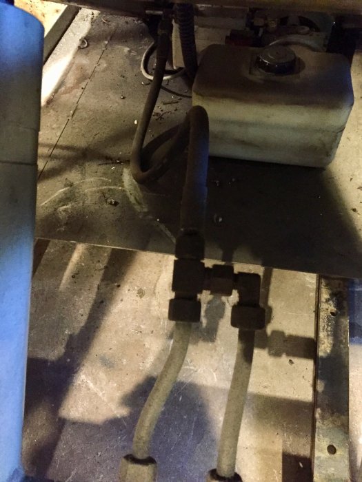 Hydraulaggregat med slangar och kolvar under ett lyftbord, möjlig kopplingspunkt för en tredje cylinder.