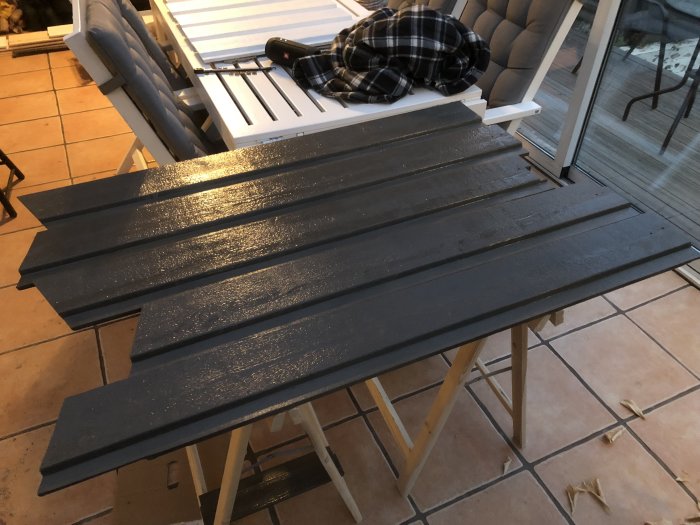 Nymålade svarta träpaneler på ett arbetsbord redo för installation.