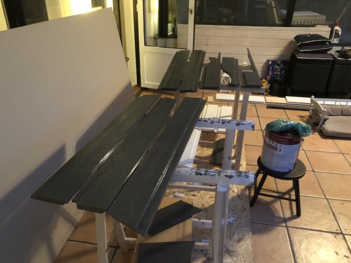 Nymålad panel och brädor för utbyte vid altan placerade inomhus att torka.