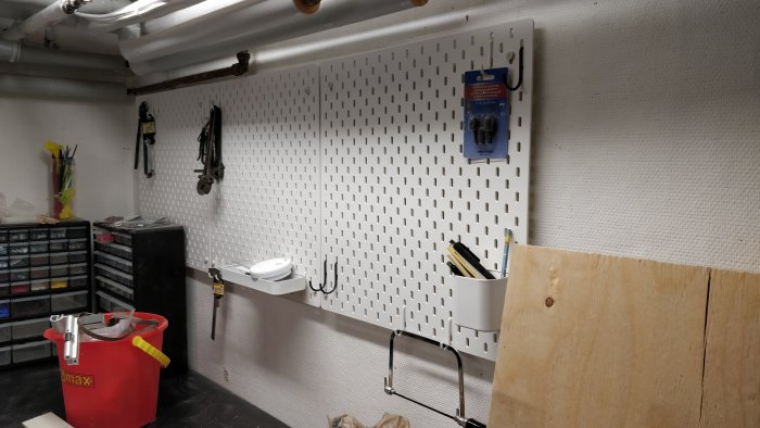 IKEA SKÅDIS pegboard monterad på lättbetongvägg med verktyg och förvaringslösningar i ett verkstadsrum.