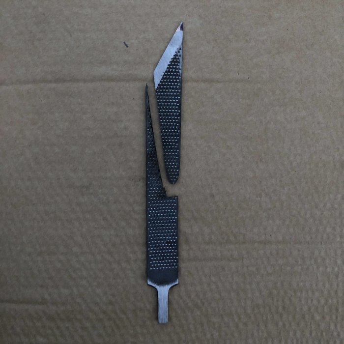 Hemgjord kniv slipad från gammal fil med texturerat handtag på brun bakgrund.