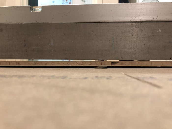 Nivåskillnad i golvet med ett vattenpass ovanpå som visar lutning mot en hall i ett hembygge.