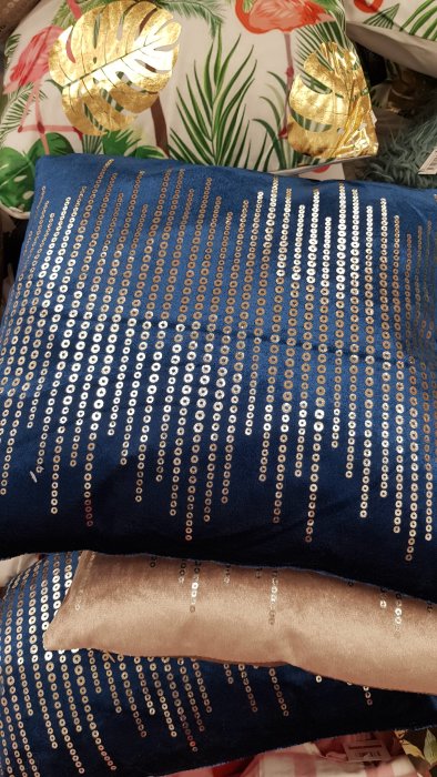 Mörkblå kuddar med skimrande paljetter som bildar vågliknande mönster.