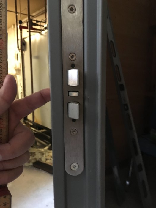 Ståldörr med öppen Assa Abloy 1728 låskista synlig och måttband till vänster.