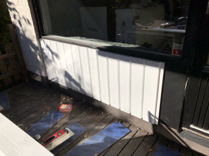 Nymonterad vit panel vid altandörr och isolering samt vindskydd på golvet i byggprojekt.
