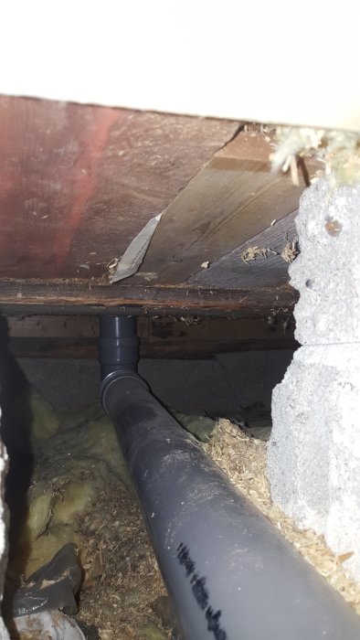 Bild på svart avloppsrör från duschen som leder in till källarens stam under husets golvbjälklag.