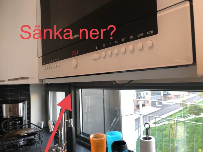 Kök med inbyggd mikrovågsugn och synlig glipa ovanför samt spalt undertill, text "Sänka ner?" och en pil som pekar på glipan.