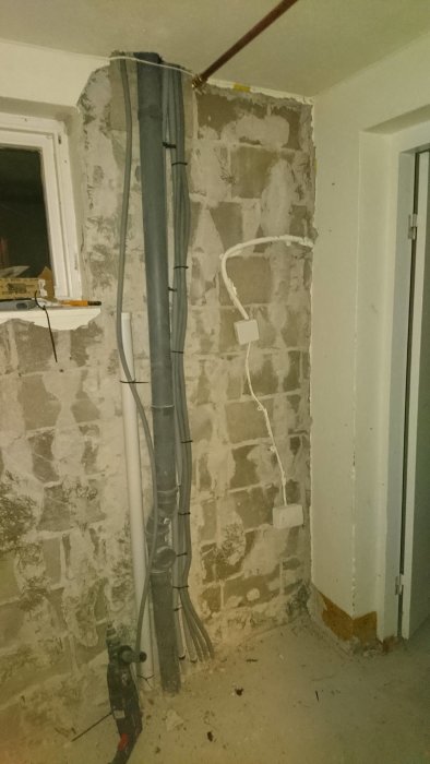 Omdraget vatten med PEX-rör och elinstallationer i en källare med synliga tegelväggar.