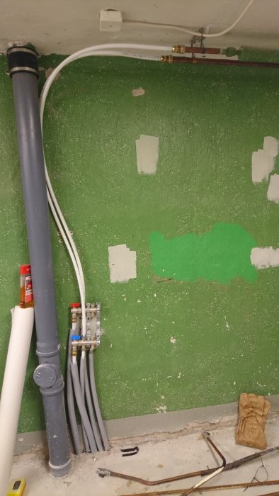Renoverat utrymme med installationer för centraldammsugare, vatten, el och avlopp, inklusive avloppsrör och fördelarskåp.