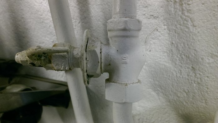 Närbild på en nyligen utbytt vit radiatorventil mot en texturerad vägg, utan synliga läckor.