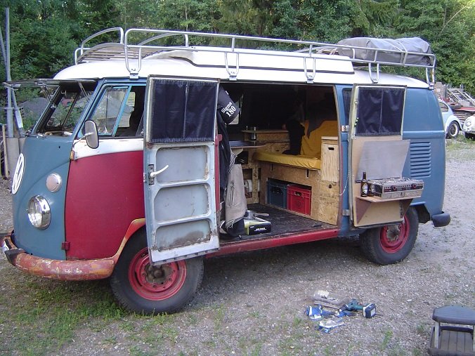 Restaurerad gammal Volkswagen minibuss med öppna dörrar och utrustning för camping.