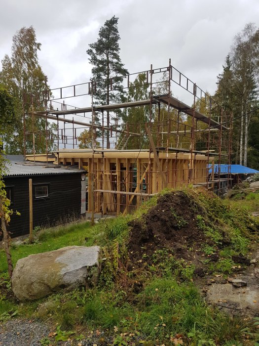 Ställning runt ett hus under konstruktion med andra våningen som pågår.