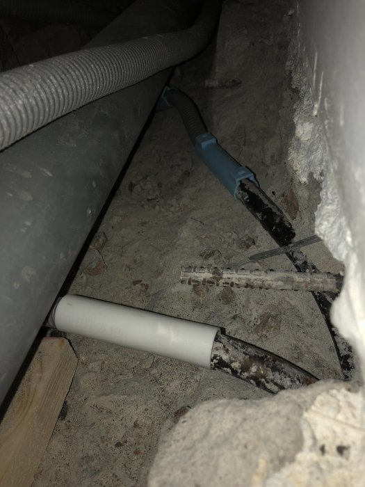 Elledningar och rör i betonggolv där elektriker åtgärdat ett kabelfel.