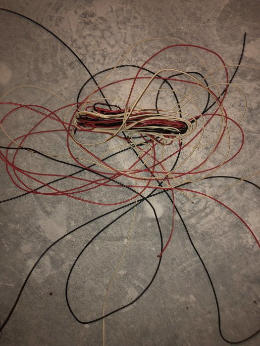 Oredigt hoptrasslade elektriska kablar på betonggolv relaterade till kabelproblem.